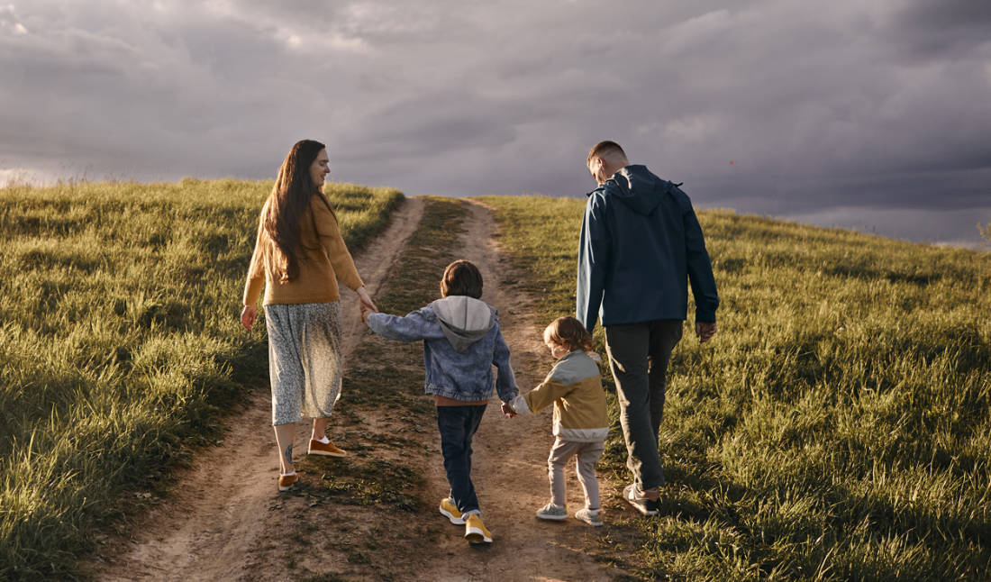 Family Walking On A Rural Dirt Road At Dusk